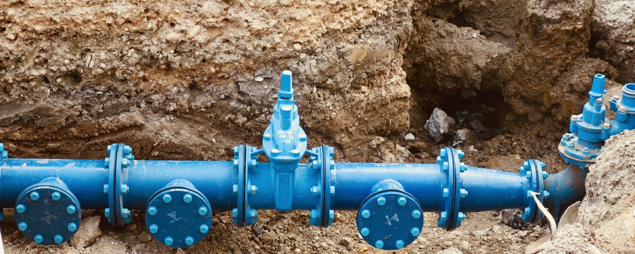 Blue pipe and valves installed in an open trench, illustrating underground infrastructure planning