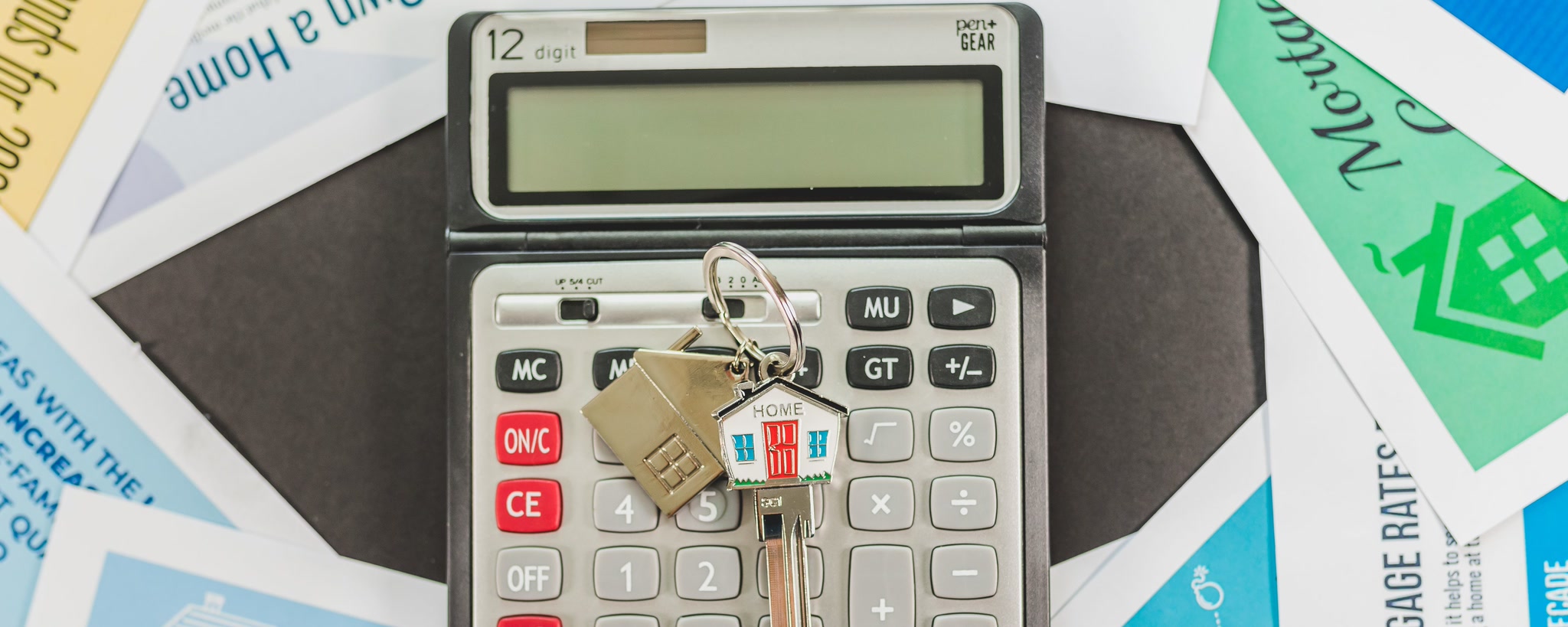 A calculator and house keys on mortgage-planning documents, illustrating a property budget review